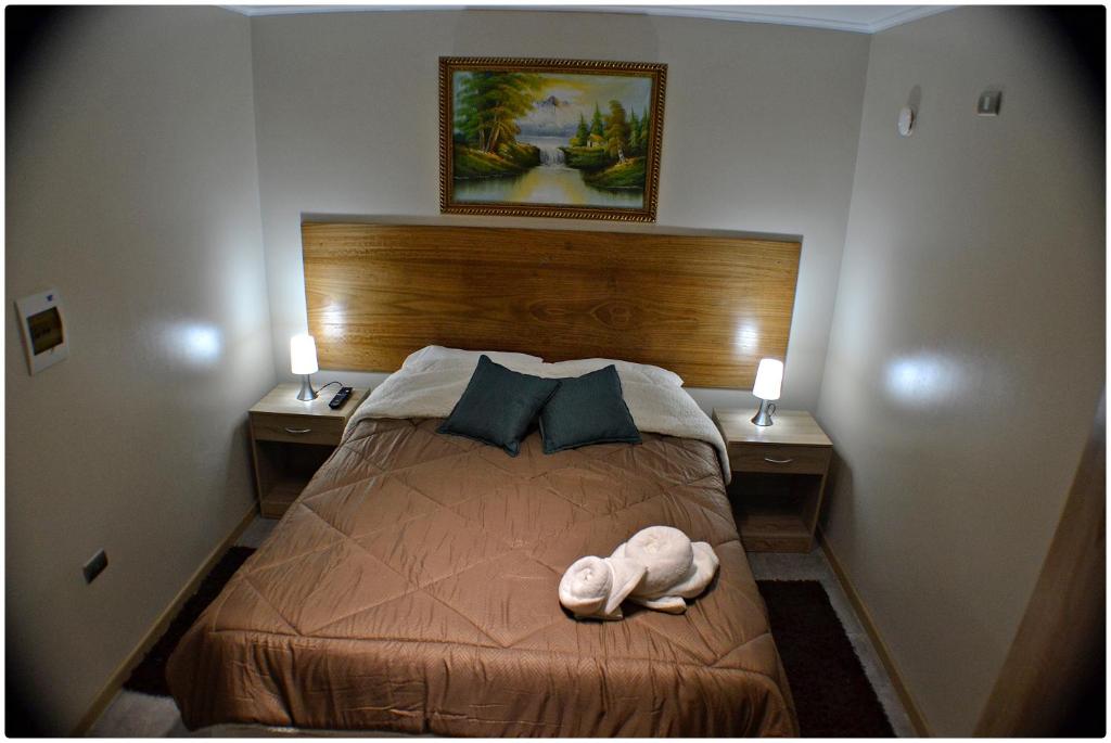 Habitación con cama grande, veladores laterales y lámparas encendidas