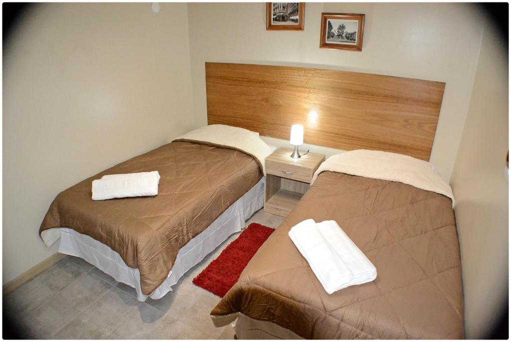 Habitación doble pequeña con dos camas individuales, velador central y lámpara